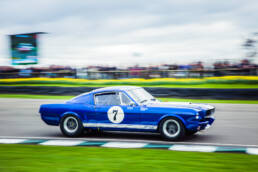 Ford Shelby Mustang GT350 with No7 marking racing with the crowd and a large screen in the background