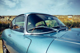 Close up photograph of a pale blue 1966 Jaguar 'E' Type Coupe featuring the windshield and roof