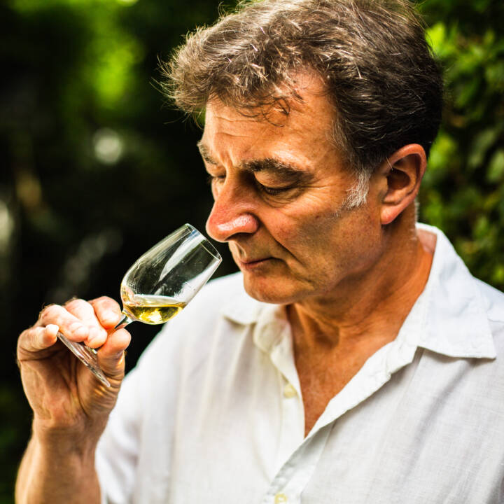 Lifestyle portrait of man in white linen shirt sniffing a dram of whisky in his garden by portrait photographer Andy Barnham
