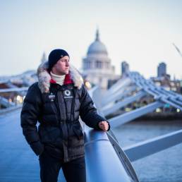 Lifestyle portrait of Scott Sears MBE, youngest person to reach the South Pole solo, standing on London's Millennium Bridge with St Paul’s Cathedral in the background. Portrait by portrait photographer Andy Barnham.