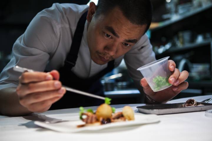 Lifestyle portrait of Michelin star Taiwanese chef André Chiang doing using tweezers to prepare to a haute cuisine dish by portrait photographer Andy Barnham