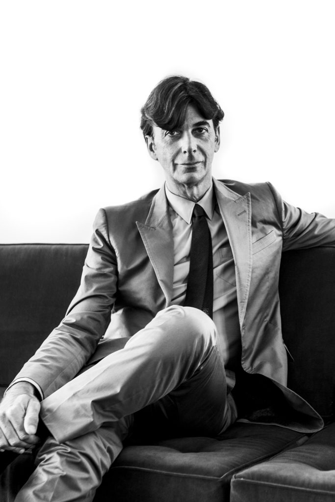Black and white portrait of former CEO Gucci Patrizio di Marco in a suit sitting on a sofa looking at the camera by portrait photographer Andy Barnham