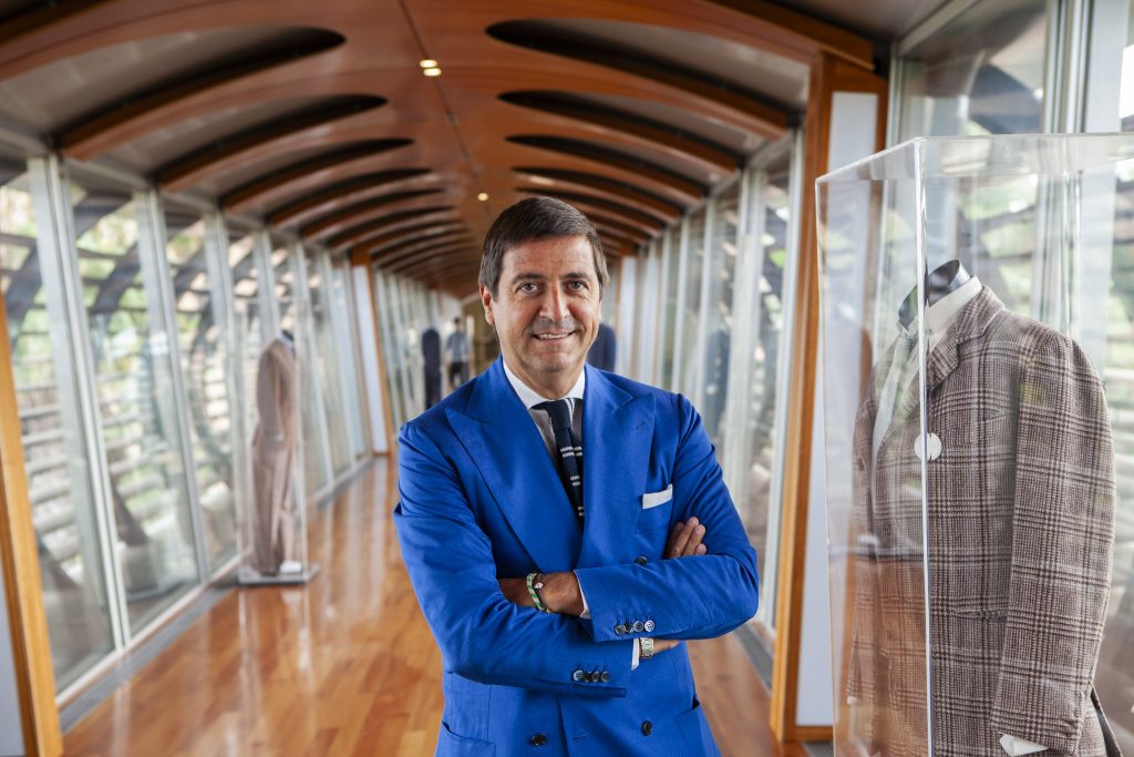 Antonio De Matteis CEO of the Kiton Group standing in the Kiton factory corridor showcasing a collection of historical garments by portrait photographer Andy Barnham
