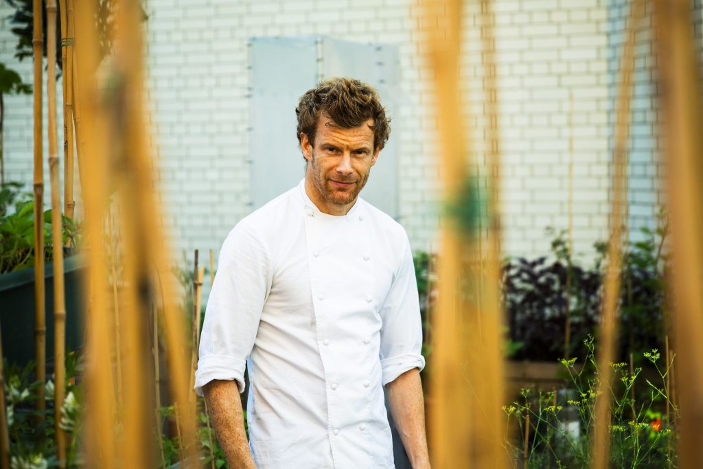 Lifestyle portrait of a English Michelin-starred chef Tom Aikens standing on a rooftop garden framed by bamboo by portrait photographer Andy Barnham