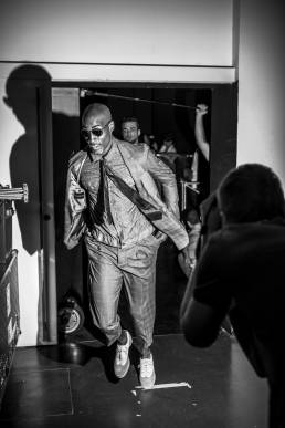 Backstage at Emporio Armani, designed by Giorgio Armani, a male model runs into the backstage area in order to change looks during a fashion show by Andy Barnham
