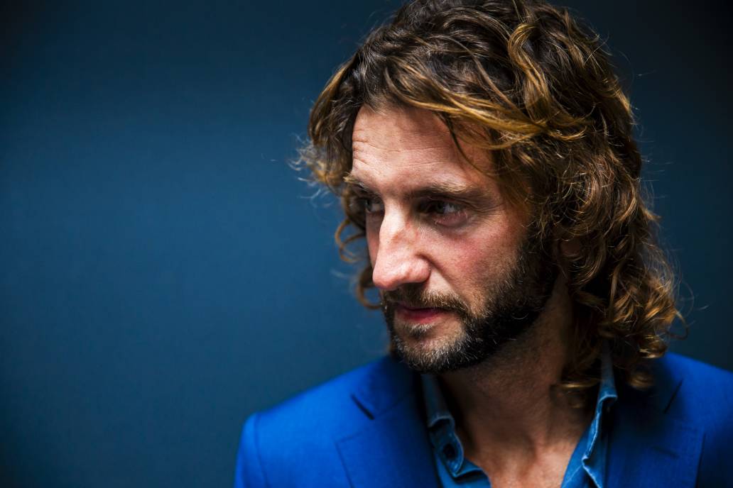 Lifestyle portrait of Swedish photographer Jacob Felländer with beard and long blonde hair in blue shirt and jacket by portrait photographer Andy Barnham