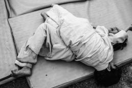 Two young girls lying on a mat practising judo