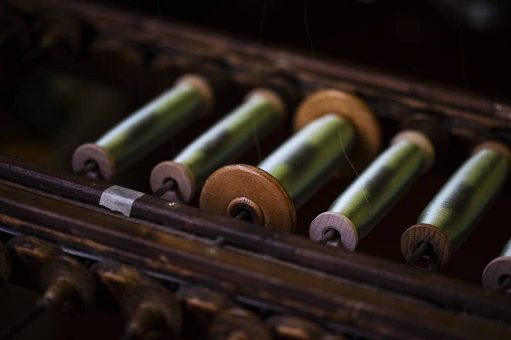 Spools of green thread sitting in a cradle in a renaissance era loom