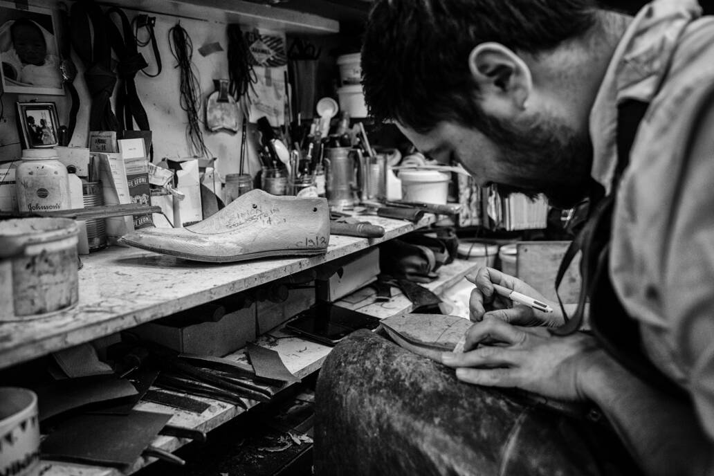 Man hand making bespoke pair of shoes in workshop
