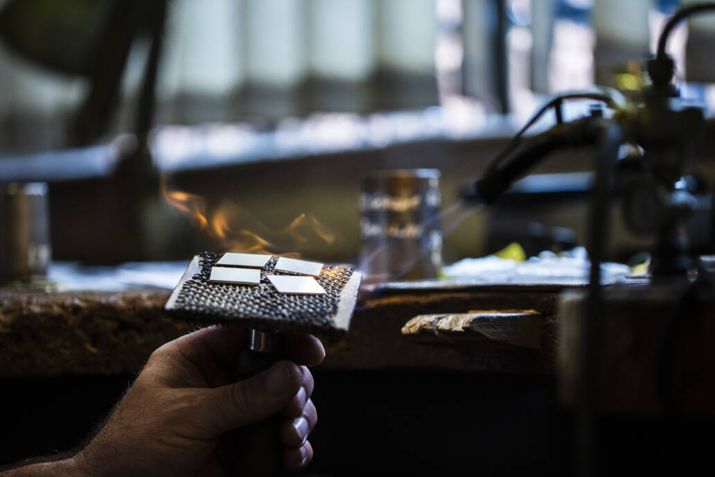 Cufflinks being crafted in a workshop under a flame