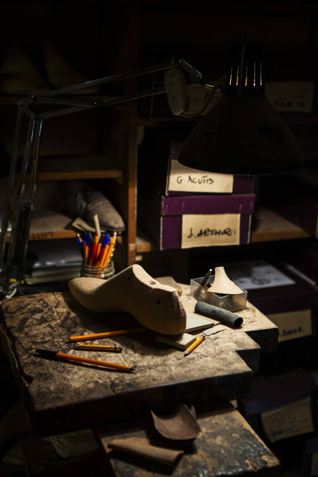 Bespoke wooden shoe last on a work bench under a lamp