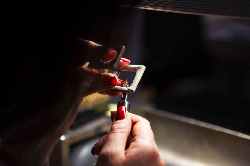 Woman with red nails inspecting a pen nib with a loupe