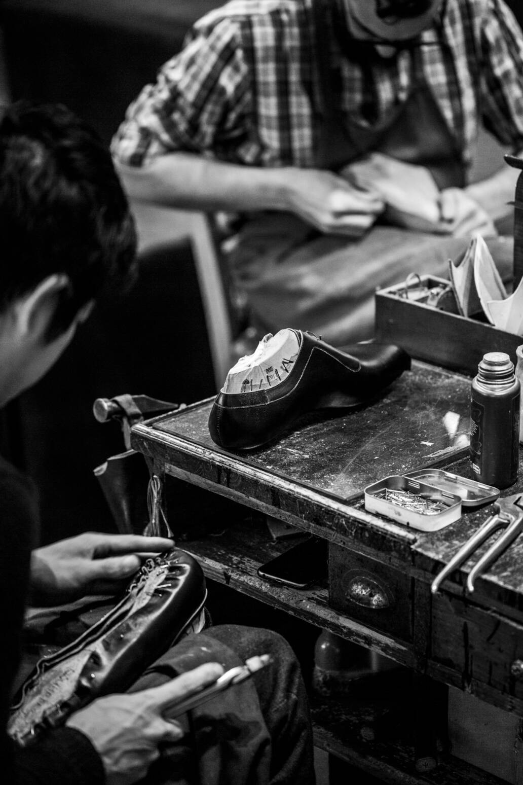Two shoe makers each making a pair of bespoke shoes