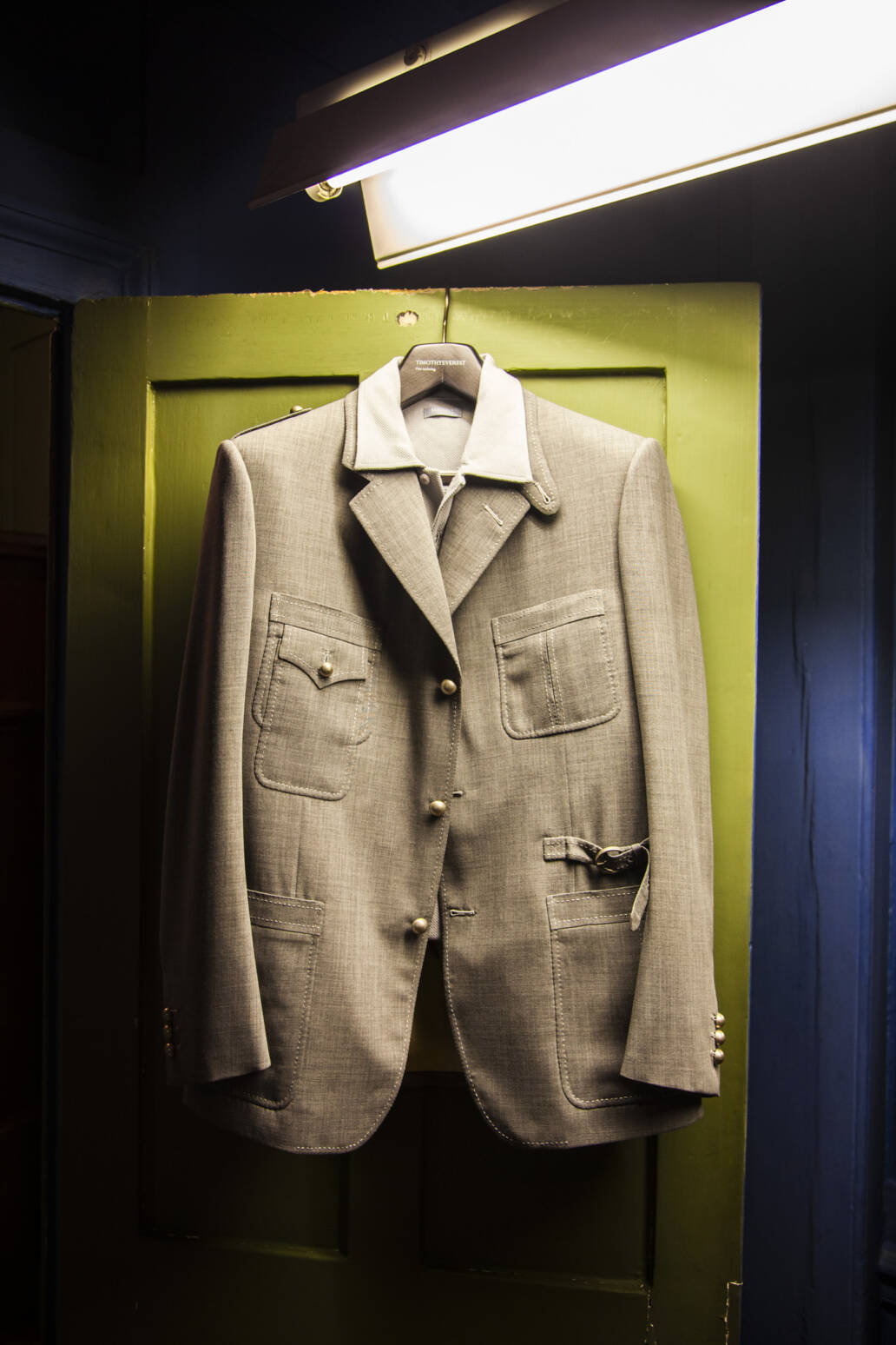 Beige safari jacket on a clothes hanger hanging on a green door