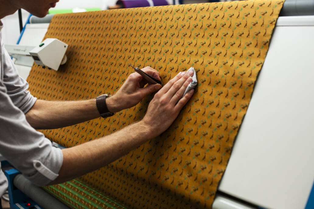 Person conducting quality control on a piece of yellow cloth