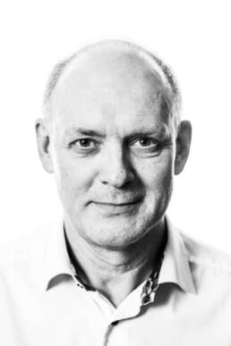 Black and white headshot of a man looking directly at the camera